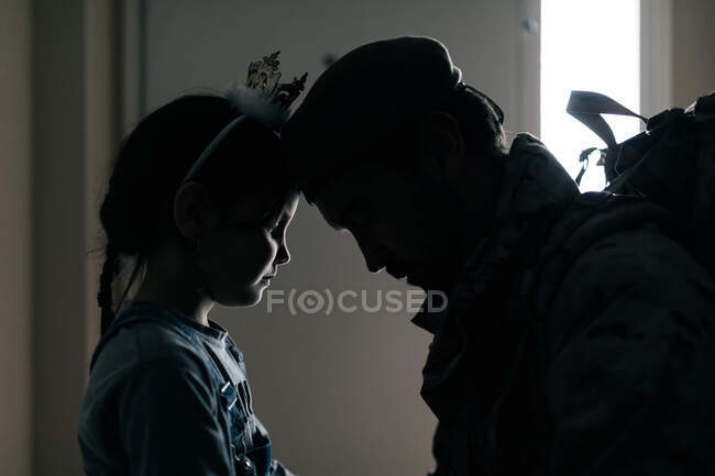 Vista lateral silhueta de menina chateada tocando o pai com a testa enquanto vê o pai para a guerra — Fotografia de Stock