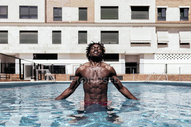 Обережно, африканський самець стоїть з закритими очима в басейні і насолоджується літньою відпусткою. — стокове фото