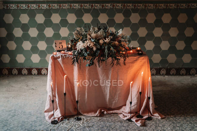 Fiori in fiore sulla tovaglia con numero e candele accese contro la parete ornamentale durante l'evento festivo in mensa — Foto stock