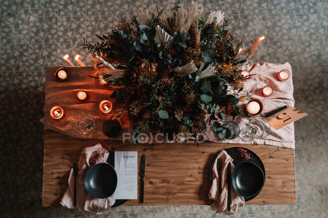 Top view of blooming flowers on tablecloth with number and burning candles during festive event in cafeteria — Stock Photo