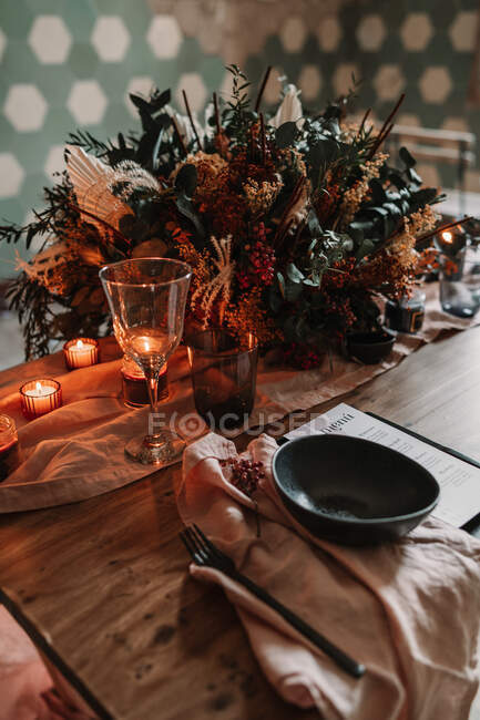 Blooming flowers on tablecloth with number and burning candles against ornamental wall during festive event in cafeteria — Stock Photo