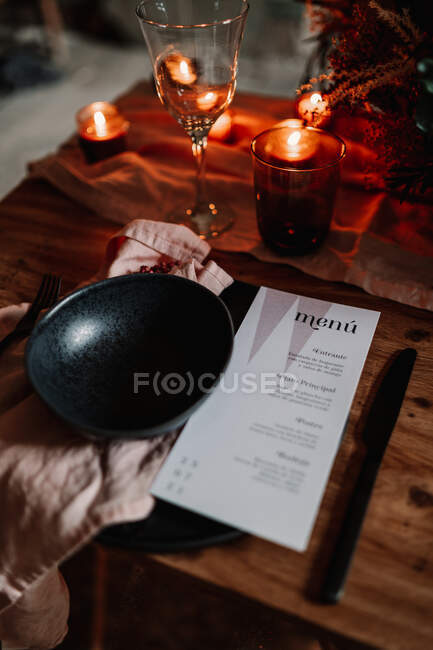 Du dessus de la feuille de papier avec la liste des menus près du bol sur le textile et brûler des bougies lors d'une occasion festive dans un café — Photo de stock