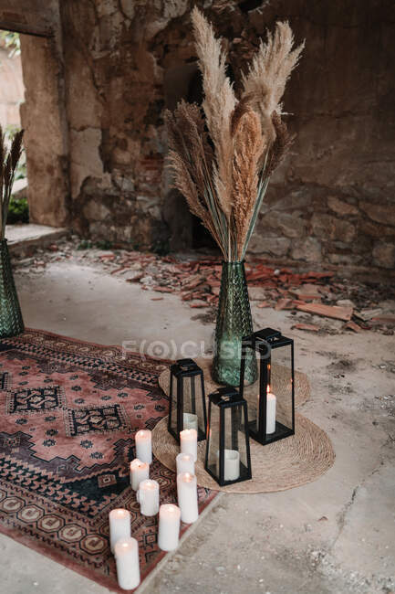 Edificio invecchiato con soffici piante secche in vasi vicino a candele e lanterne ardenti su tappeti ornamentali — Foto stock
