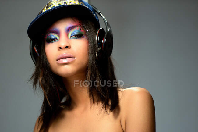 Retrato de mulher morena com cabelos longos e olhos de maquiagem ouvindo música com fones de ouvido — Fotografia de Stock