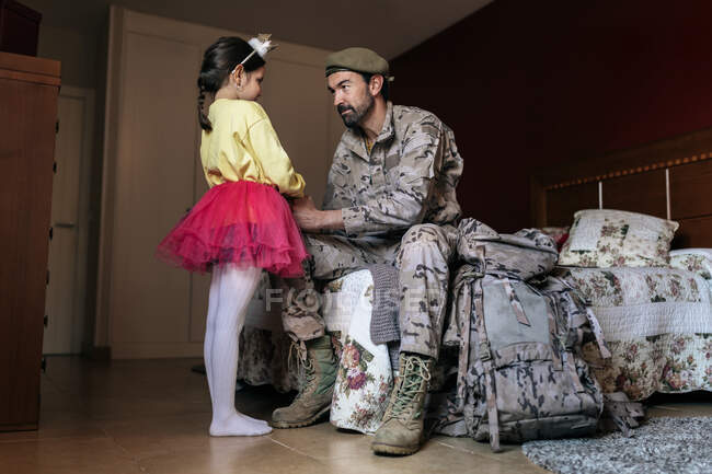 Low angle full body of fighter holding hands of small girl before going to defend country — Stock Photo