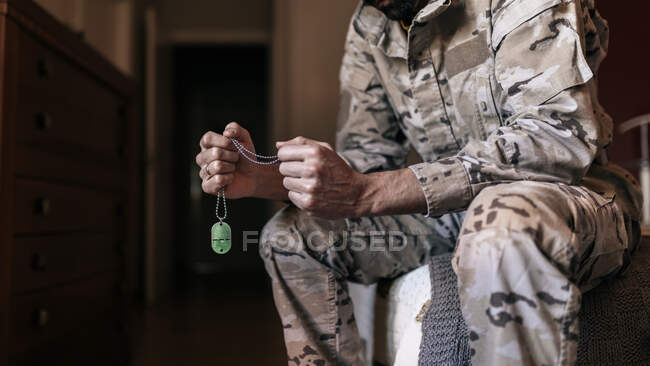 Angolo basso di un soldato senza volto, con il distintivo del nome, mentre si prepara per il servizio militare a casa. — Foto stock