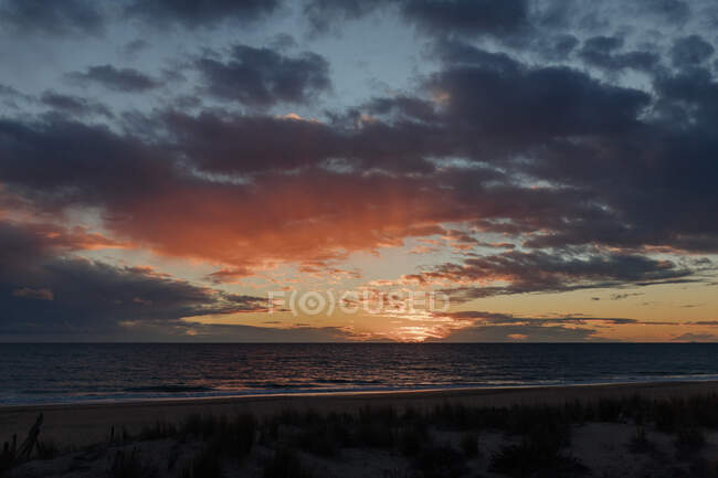 Paesaggio pittoresco di mare ondulato senza fine con costa sabbiosa contro sorprendente cielo nuvoloso tramonto — Foto stock
