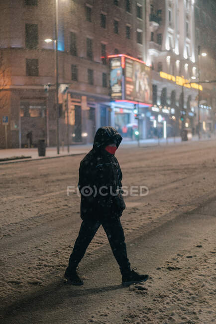 Vista lateral do homem anônimo em outerwear andando na estrada no inverno nevado em Madrid Espanha — Fotografia de Stock