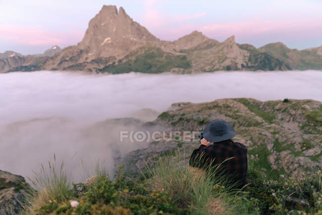 De cima visão traseira de turista masculino anônimo tirando foto de montagem em nevoeiro na câmera sob céu nublado — Fotografia de Stock