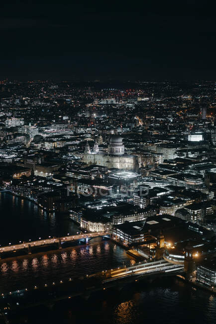 Vue pittoresque sur drone des ponts sur la rivière qui coule à travers la ville de Londres avec des bâtiments éclairés et des rues la nuit — Photo de stock