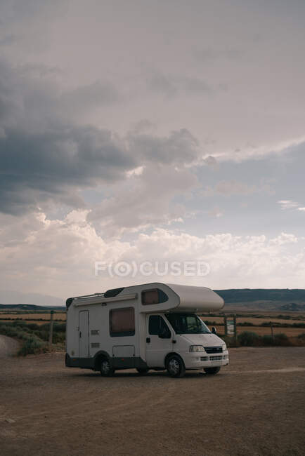 Motorhome estacionado em terreno arenoso contra o céu nublado rocha durante o dia — Fotografia de Stock