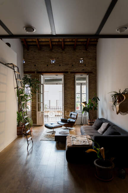 Interior de la sala de estar con plantas en maceta verde y cómodo sofá en estilo loft - foto de stock