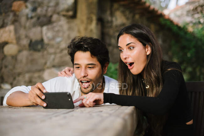 Jeune couple regardant mobile tout en s'amusant — Photo de stock