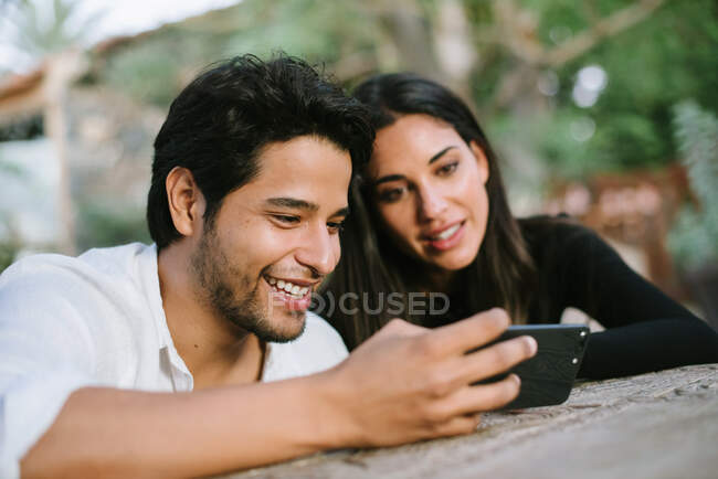 Jovem casal olhando para celular enquanto se diverte — Fotografia de Stock