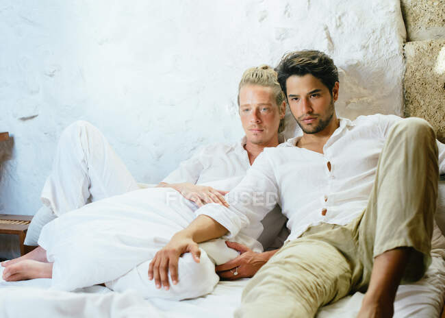 Два чоловіки сидять на ліжку, дивлячись геть — стокове фото