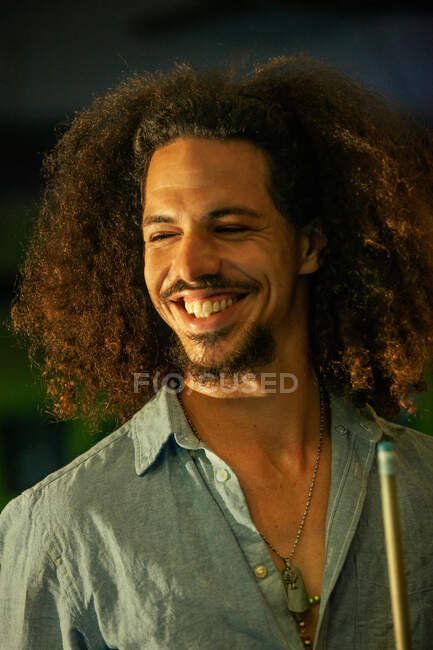 Ethnic male player rubbing tip of billiard cue with chalk before hitting ball — Stock Photo