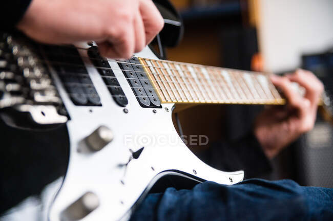 Low angle side view of concentrated blind guitarist playing music instrument while rehearsing melody at home — Stock Photo