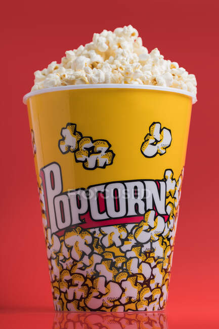 Bowl full of popcorn on a red background — Stock Photo