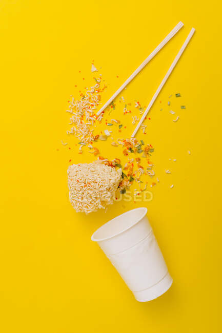 Top view composition of instant noodles with spices scattered near plastic package on vivid background — Stock Photo