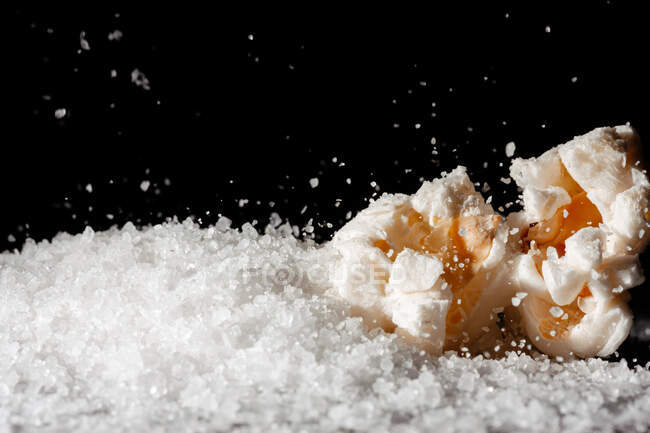 Крупный план вкусного попкорна на слое соли — стоковое фото
