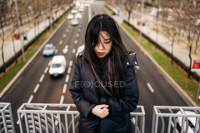 Long hair brunette asian woman standing on a bridge and looking down — Stock Photo