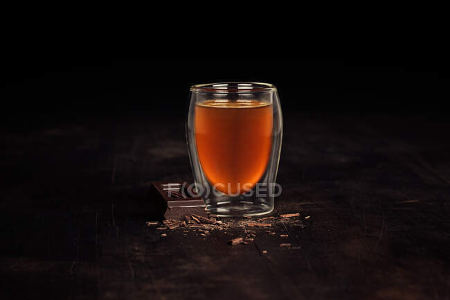 Primer plano de un vaso de té con un chocolate - foto de stock