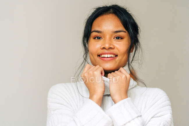 Long-haired brunette Asian woman dressed in a white sweater looking at camera — Stock Photo