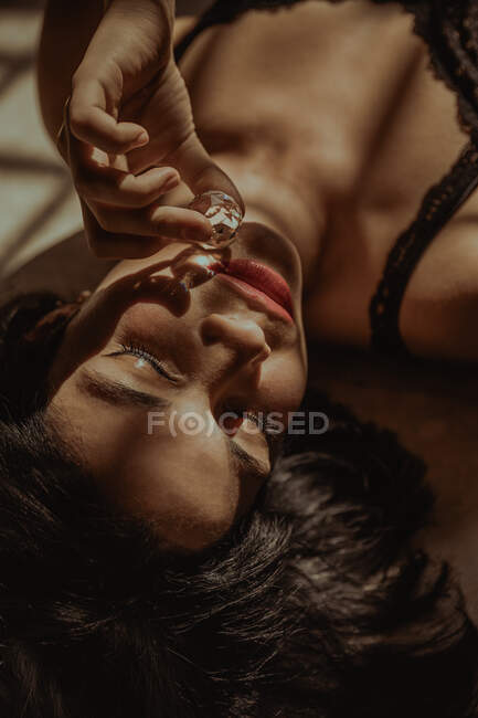 Зверху ніжна жінка лежить зі скляним кристалічним м'ячем, що відображає сонячне світло в кімнаті — стокове фото