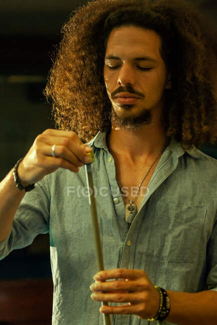 Serious ethnic male player rubbing tip of billiard cue with chalk before hitting ball — Stock Photo