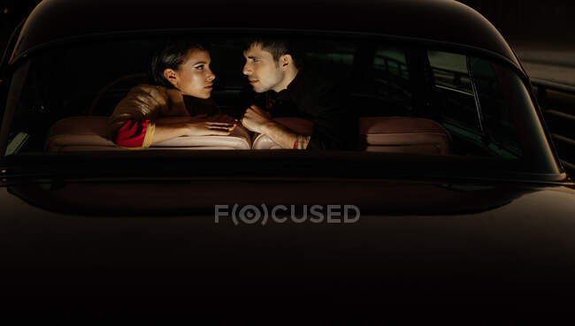 Seitenansicht eines multiethnischen Paares, das zusammen auf dem Rücksitz eines altmodischen Autos sitzt — Stockfoto