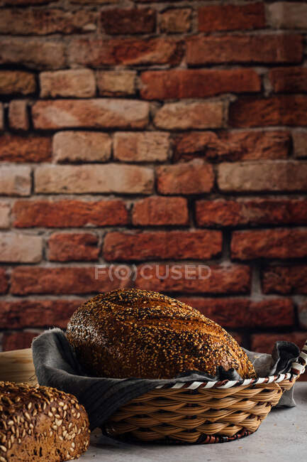 Delicioso pão integral em cesta de palha na mesa — Fotografia de Stock