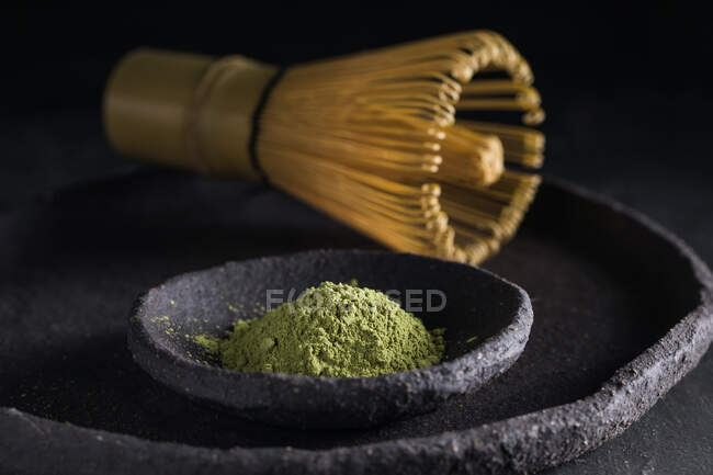 Dried tea leaves in heap on plate with chasen for tea ceremony — Stock Photo