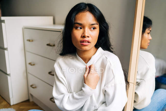 Длинные волосы брюнетка азиатская женщина носит белый свитер и смотрит в сторону — стоковое фото