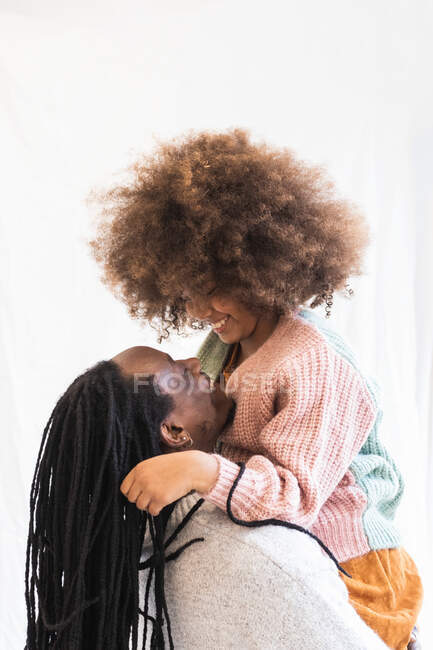 Vue latérale de père afro-américain heureux embrassant fille tout en portant sur les mains et en se regardant — Photo de stock