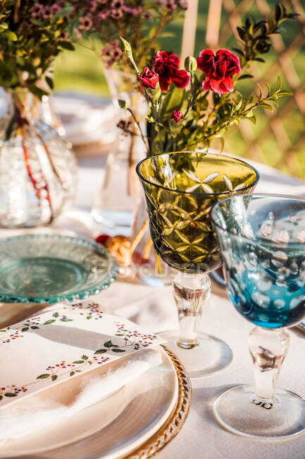 Angle élevé de table de fête servie avec des verres en cristal serviette de coutellerie sur l'assiette près de bouquet de fleurs fraîches pour mariage et carte de menu — Photo de stock