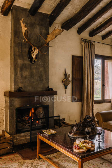 Interno di casa rustica con camino e corna di cervo appese al muro — Foto stock