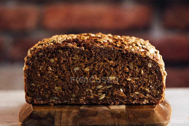Delicious wholegrain bread on cutting board on table — Stock Photo