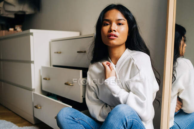 Long hair brunette Asian woman wearing a white sweater and looking at camera — Stock Photo
