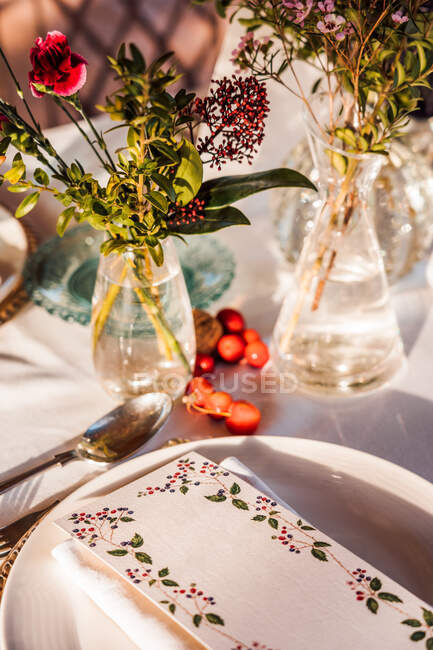 Високий кут подачі святкового столу з кришталевими келихами столярна серветка на тарілці біля букету свіжих квітів для весілля та картки меню — стокове фото