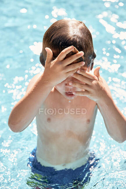 Веселый маленький мальчик без рубашки кричит во время прыжков в воду бассейна во время летних каникул в сельской местности — стоковое фото