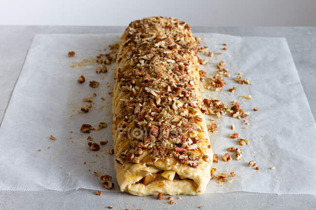 From above tasty apple pastry with crunchy nut pieces on baking paper on countertop — Stock Photo