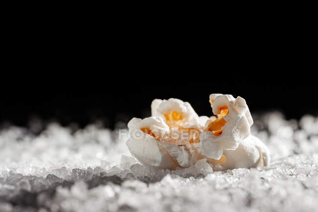 Primo piano di un delizioso popcorn su uno strato di sale — Foto stock