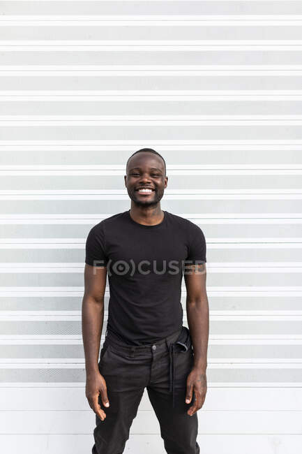 Зміст афроамериканського чоловіка в чорній футболці, що дивиться на камеру на світлому фоні — стокове фото