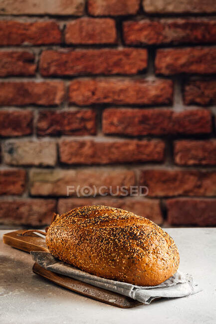 Вкусный цельнозерновой хлеб на доске на столе — стоковое фото