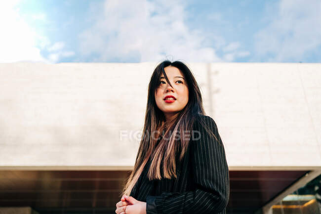 Long hair brunette asian woman standing on stairs and looking away — Stock Photo