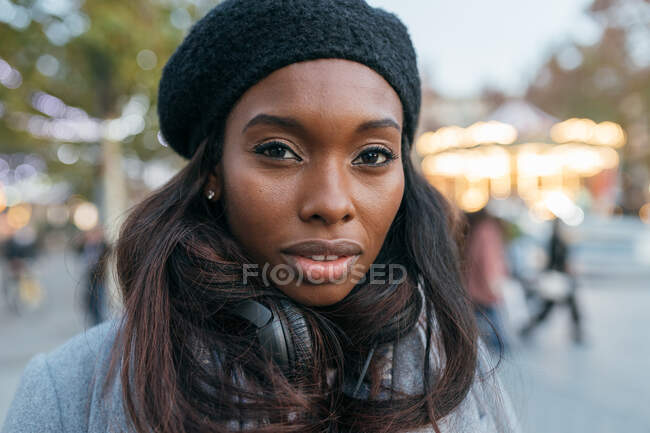 Close-up afro-americano feminino de pé na rua outerwear e com fones de ouvido — Fotografia de Stock