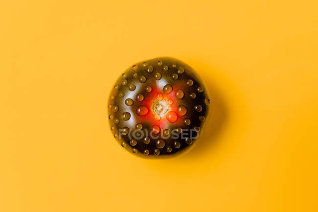 Overhead view of ripe tomato with pure water drips representing doughnut with chocolate glaze concept — Stock Photo