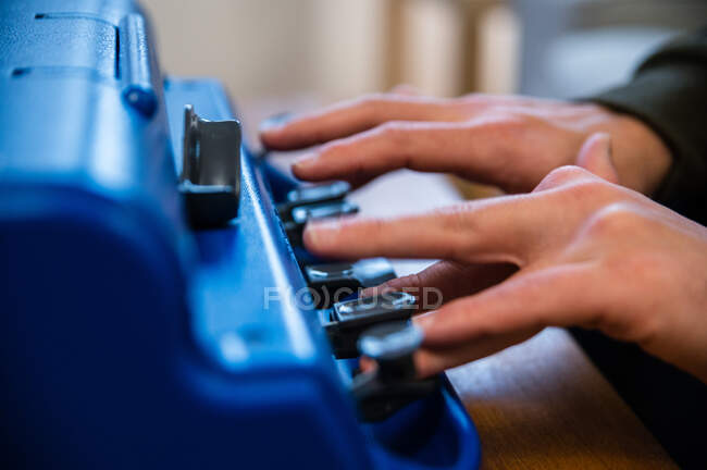 Анонимный мужчина с нарушением зрения, печатает на машинке с тактильной системой письма дома — стоковое фото