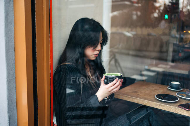 Morena de cabelos compridos Mulher asiática tomando um café em uma cafeteria — Fotografia de Stock