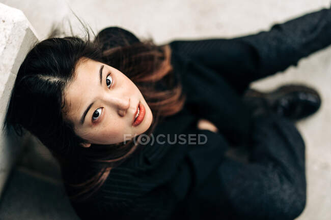 Capelli lunghi bruna donna asiatica seduta su alcune scale e guardando la fotocamera — Foto stock